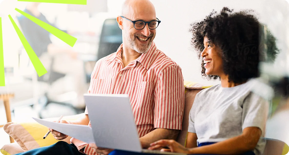 Two teammates smiling while working together at a laptop